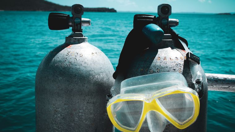 Scuba tanks and dive mask staged on a boat over open water